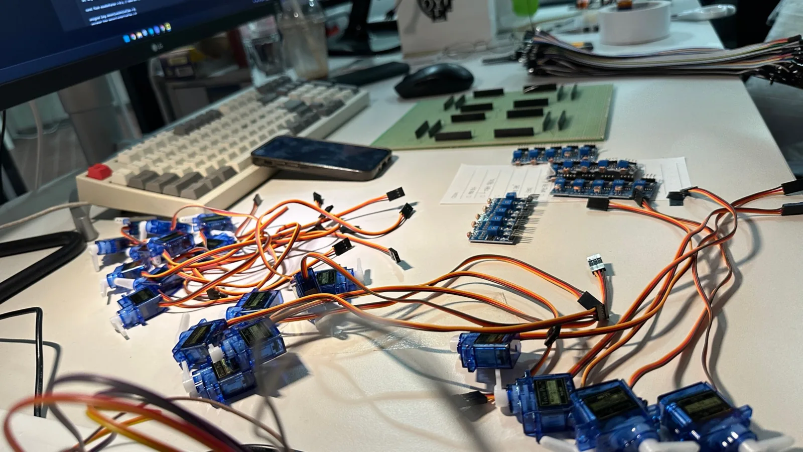 A dozen or so servos, light sensor modules, and perfboards scattered on a desk.